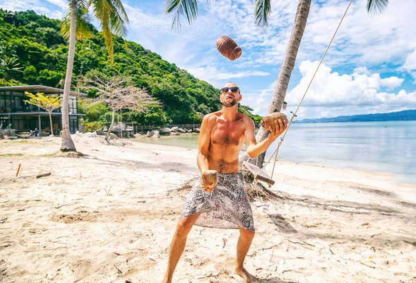 Jeune homme drôle jonglant noix de coco sur la plage — Photo