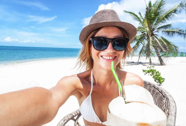 Mulher bonita com um coco em suas mãos faz selfie o — Fotografia de Stock