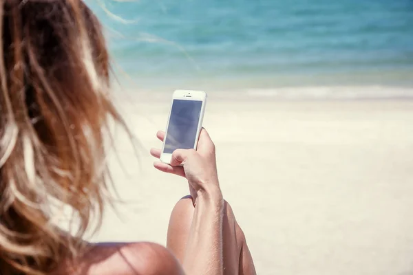 Handy mit Frauenhänden am Strand und blauem Meer — Stockfoto