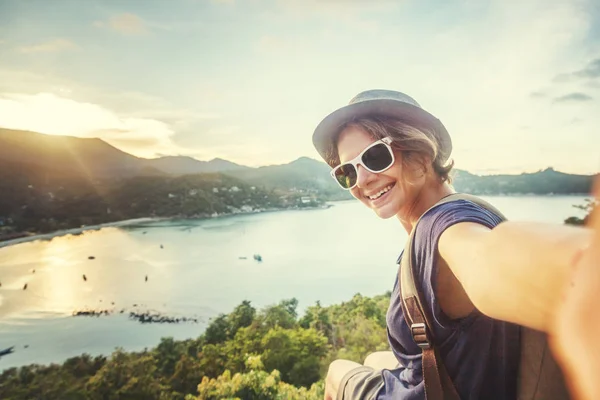 Young woman traveler in sunglasses makes selfie with sea view — Stock Photo, Image