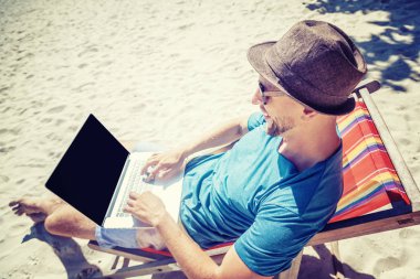 Sahilde çalışma dizüstü bilgisayar ile çekici genç adam. Özgürlük, 