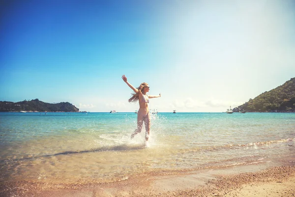 Hermosa joven con el pelo largo corre a lo largo de una playa tropical —  Fotos de Stock