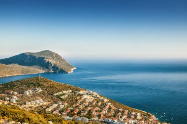 Beyaz binalar ve sahilde turuncu çatı ile küçük bir şehir 