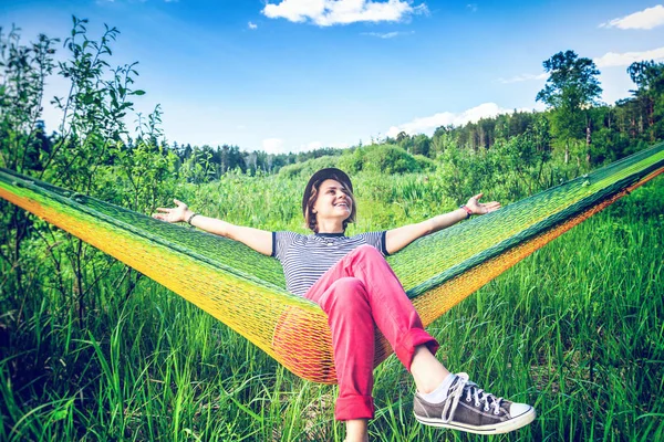 Bella giovane donna hippy su un'amaca in un campo estivo verde — Foto Stock