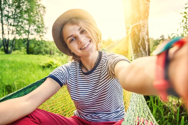 Giovane donna felice oscillare su un'amaca e fare selfie nel — Foto Stock