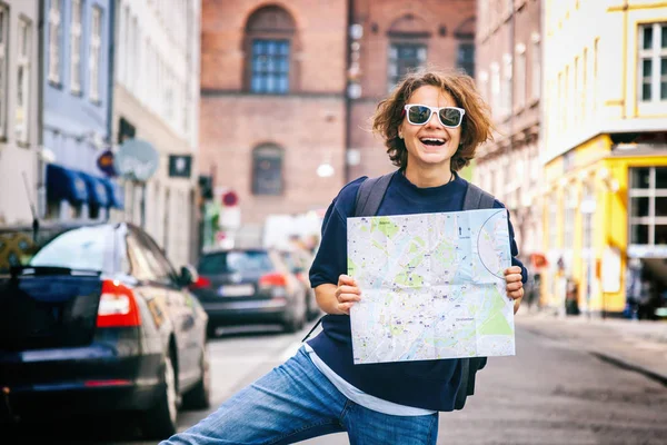 Happy young woman traveler with map in hand on the background of