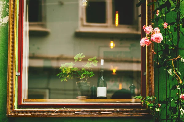 Fenster mit Spiegelungen, Flasche Wein, Straße, Blumen, Bild — Stockfoto