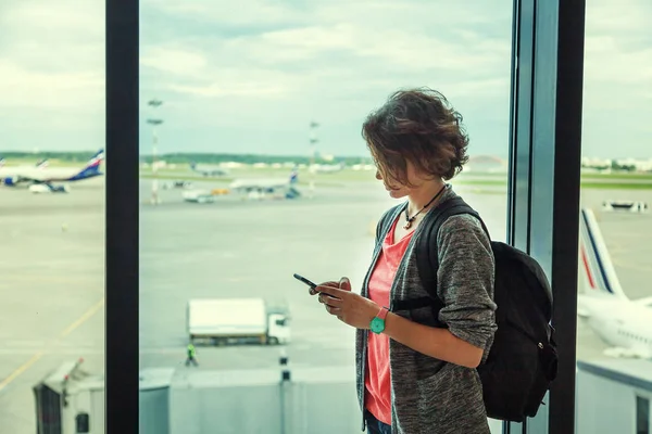 Young woman traveler at the airport with a mobile phone in hands
