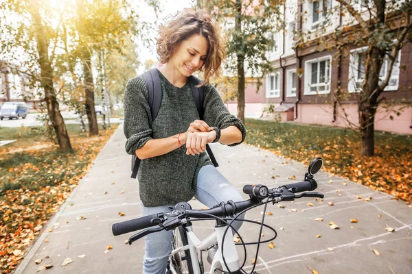 Ung vacker kvinna på en cykel använder en smartwatch, navigering — Stockfoto