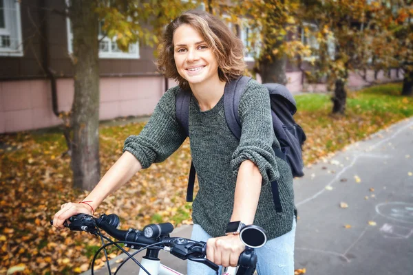 Güzel genç kız öğrenci bir kazak ve bir bicyc kot
