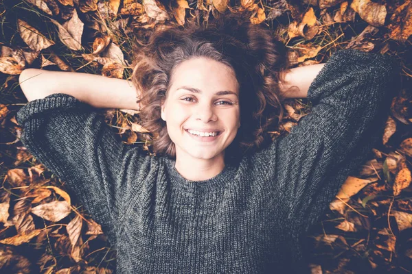 Giovane bella donna si trova sul fogliame autunno nel parco — Foto Stock
