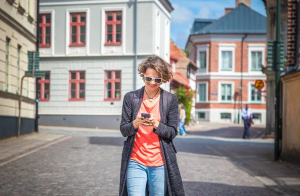 Молодая красивая стильная женщина с мобильным телефоном в руках на город — стоковое фото