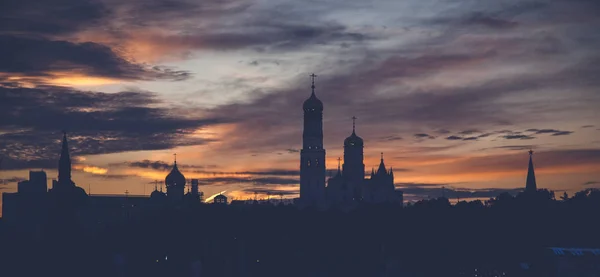 Donkere silhouet van gebouwen tegen de achtergrond van een helder — Stockfoto