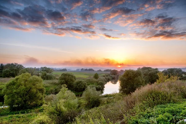 Прекрасний захід сонця з видом на поля, пагорби і річку. Яскравий — стокове фото