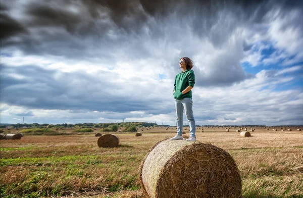 Krásná mladá žena stojící na sena proti poza — Stock fotografie