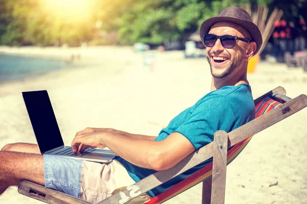 Привлекательный молодой человек с ноутбуком, работающий на пляже. Свобода , — стоковое фото