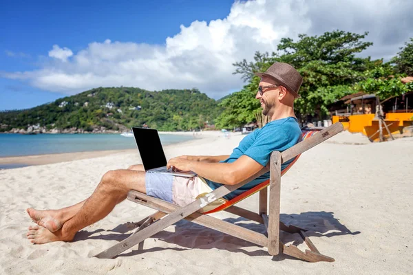 Ελκυστικό νεαρό άνδρα με φορητό υπολογιστή που εργάζονται στην παραλία. Ελευθερία, — Φωτογραφία Αρχείου