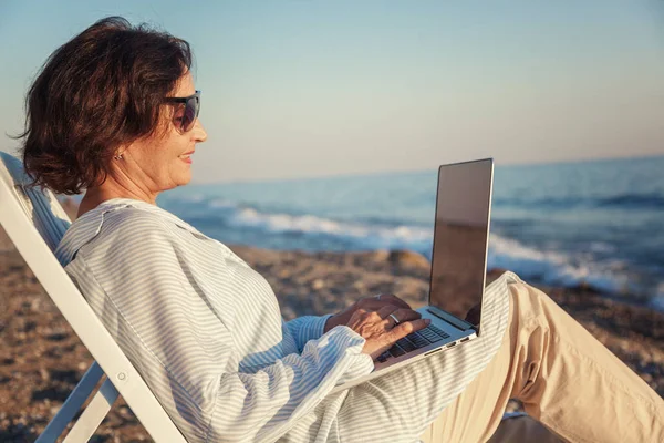 Κομψή ελκυστική ώριμη γυναίκα 50-60 κάνει χρήση του φορητού υπολογιστή για το — Φωτογραφία Αρχείου