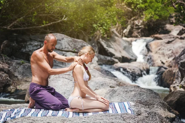 Un homme fait un massage pour une femme dans la nature à côté d'un wat — Photo