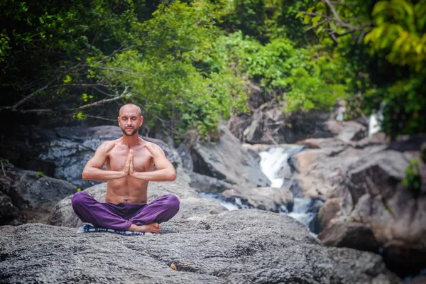Un joven atractivo se sienta en una pose de loto y medita de nuevo — Foto de Stock