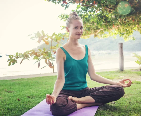 Hermosa joven rubia haciendo yoga en la orilla de una tropica — Foto de Stock