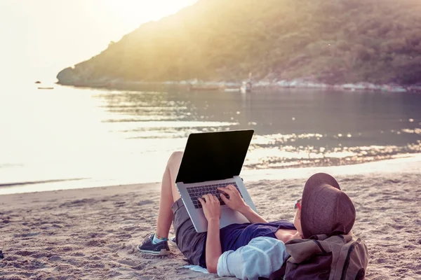 Νεαρή γυναίκα χρησιμοποιεί το φορητό υπολογιστή σε μια παραλία. Con δουλειά freelance — Φωτογραφία Αρχείου
