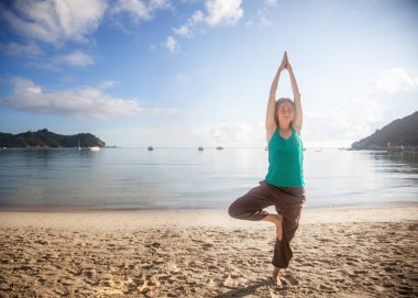 güzel genç sarışın kadın bir tropica kıyısında yoga yaparken