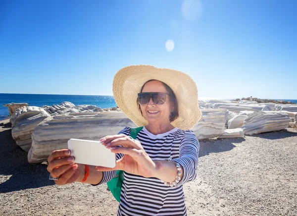 Olgun güzel kadın yolcunun cep telefonu fotoğraf çeker. — Stok fotoğraf