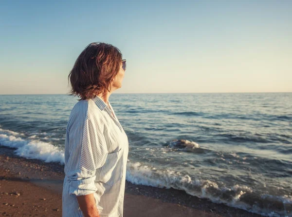 Belle vieille femme debout sur la plage et admirant la mer un — Photo