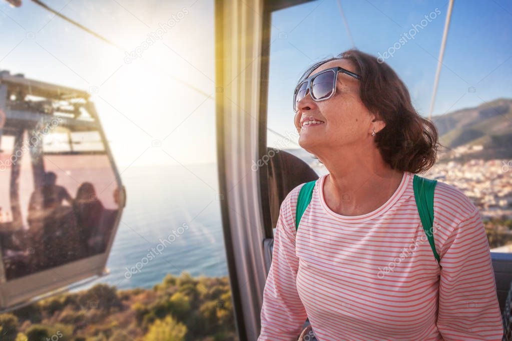 An elderly beautiful woman travels, admiring the view from the c
