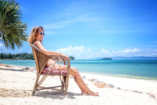 Una hermosa joven en bikini blanco se sienta en un bea tropical —  Fotos de Stock