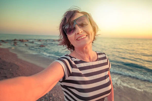 Stylish attractive mature woman 50-60 makes selfie on mobile pho — Stock Photo, Image