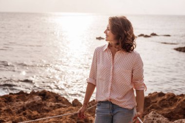 Güzel genç kıvırcık şık kız kot pantolon ve gömlek pembe bir 