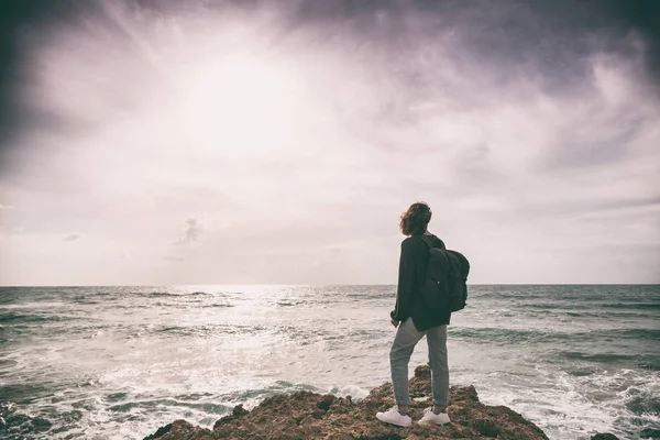 Una chica con una mochila está de pie con su espalda en la tormenta s — Foto de Stock