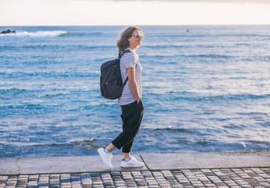 genç güzel kadın kız bir sırt çantası ile seash yürür