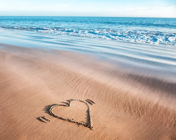 Сердце, нарисованное в песке на берегу океана, концепция о — стоковое фото