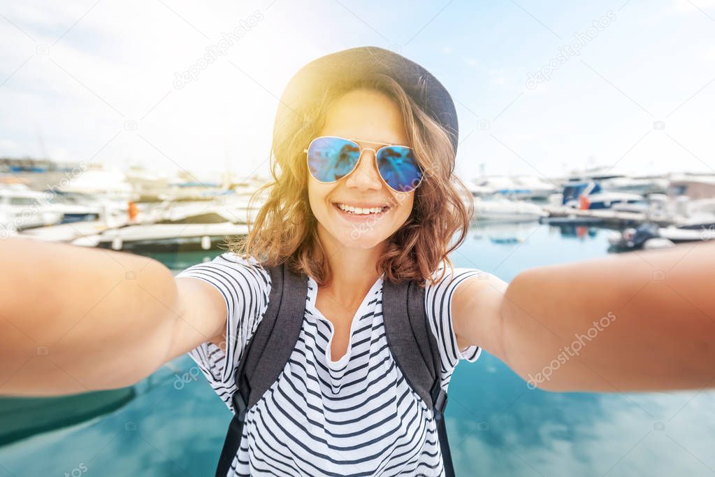young beautiful woman traveler in a hat makes selfie on a smartp