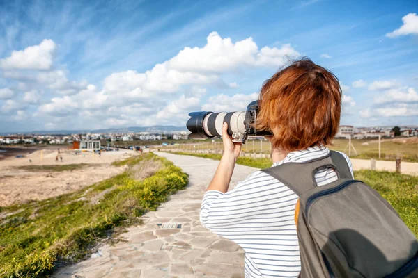 Jovem fotógrafa viajante com uma mochila fazendo uma foto — Fotografia de Stock