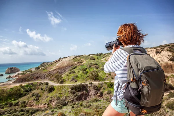 Young woman traveler with a camera in the hands of a background — Stock Photo, Image