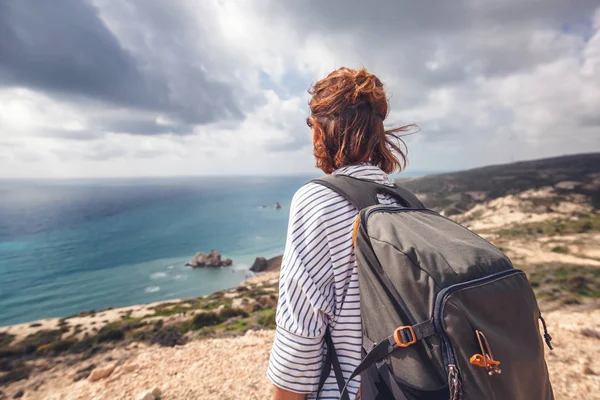 A young traveler woman with a backpack on a stunning landscape b — Stock Photo, Image