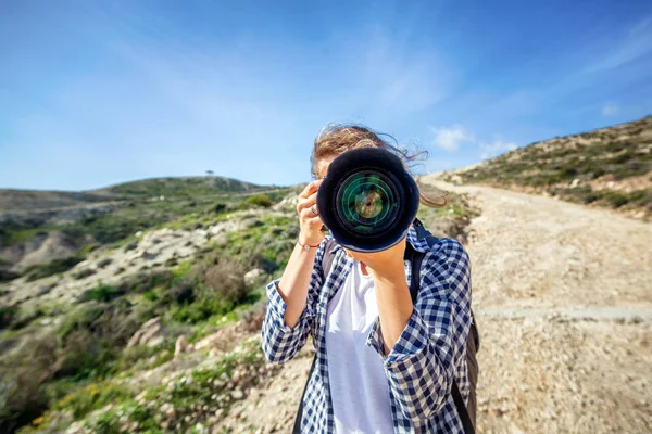 Κορίτσι ταξιδιώτης με μια φωτογραφική μηχανή στο χέρι, ενάντια σε έναν όμορφο καλοκαιρινό — Φωτογραφία Αρχείου
