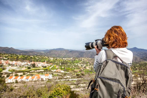 Een jonge vrouw reiziger met een rugzak en de camera schiet een beaut — Stockfoto