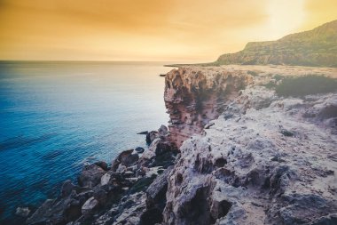 Parlak güzel gün batımı deniz kenarında çarpıcı. Kayalar ve masmavi blu