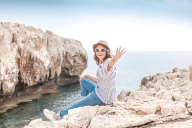 Genç güzel kadın seyahat kız şapka ve güneş gözlüğü oturur 