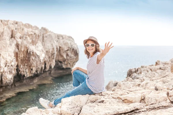 Young beautiful woman travel girl in hat and sunglasses sits on