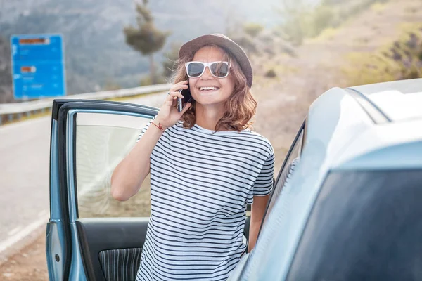 Young beautiful female travel girl in hat and sunglasses speaks