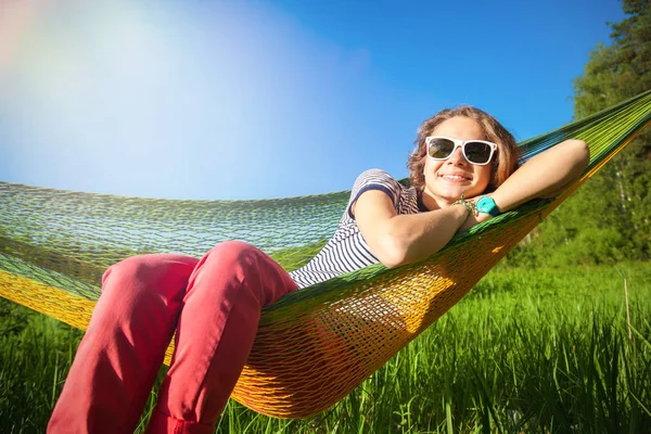 Happy young hipster girl enjoys life and nature on a hammock in — Stock Photo, Image