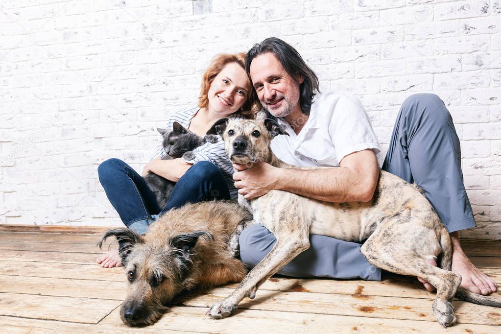 Attractive man and his young wife with pets, two dogs and a cat,