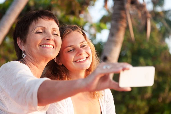 Äiti ja aikuinen tytär tekevät selfie matkapuhelimella su — kuvapankkivalokuva