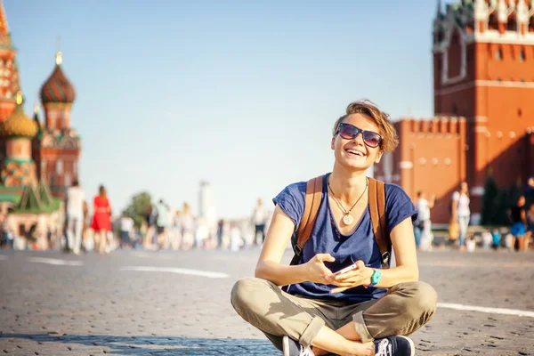 Красивая молодая студентка, сидящая на тротуаре на Красном — стоковое фото